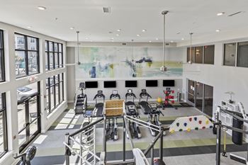 The lobby of a gym with chairs and a large wall of windows